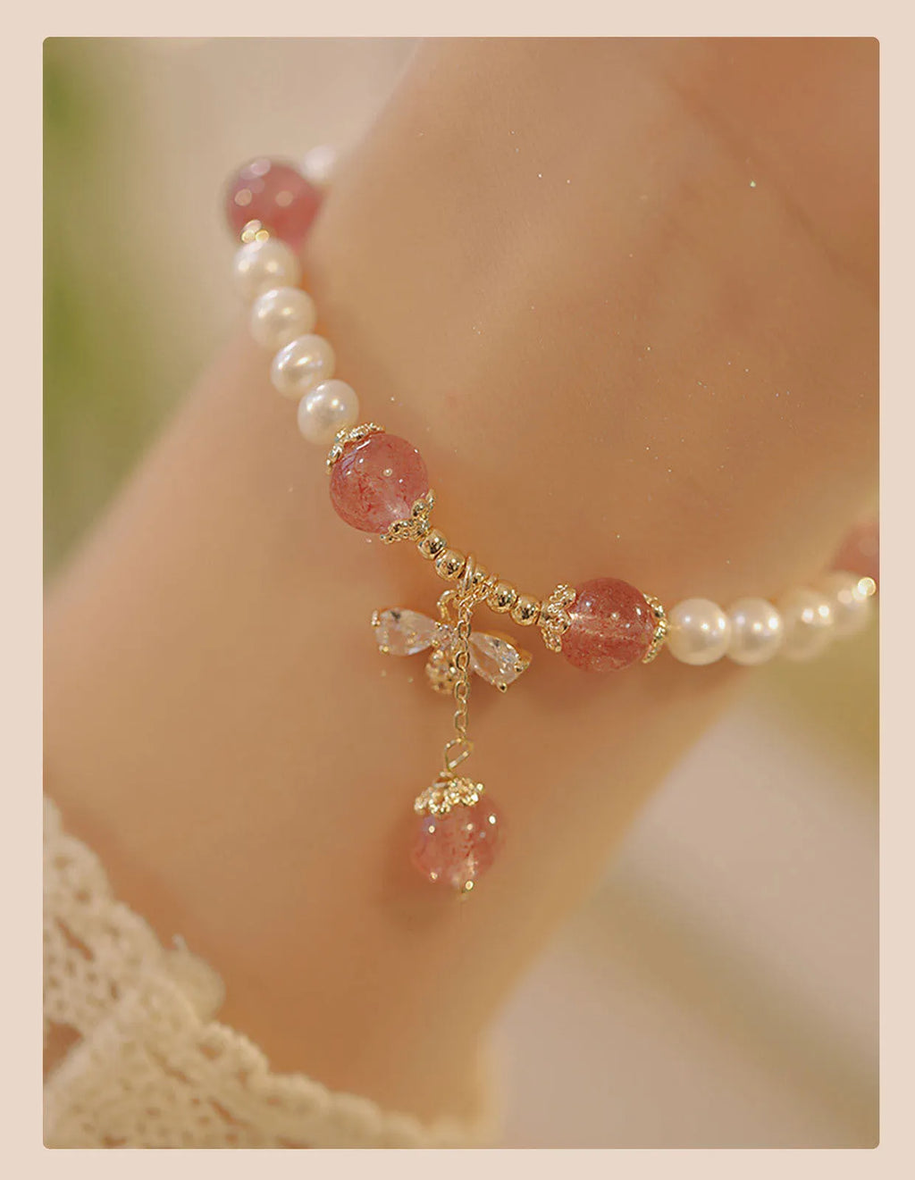 Women's strawberry quartz crystal bracelet with pearls and bow charm on wrist