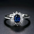 Copper women's ring with floral band and inlaid blue zirconium stone, shown on a finger.