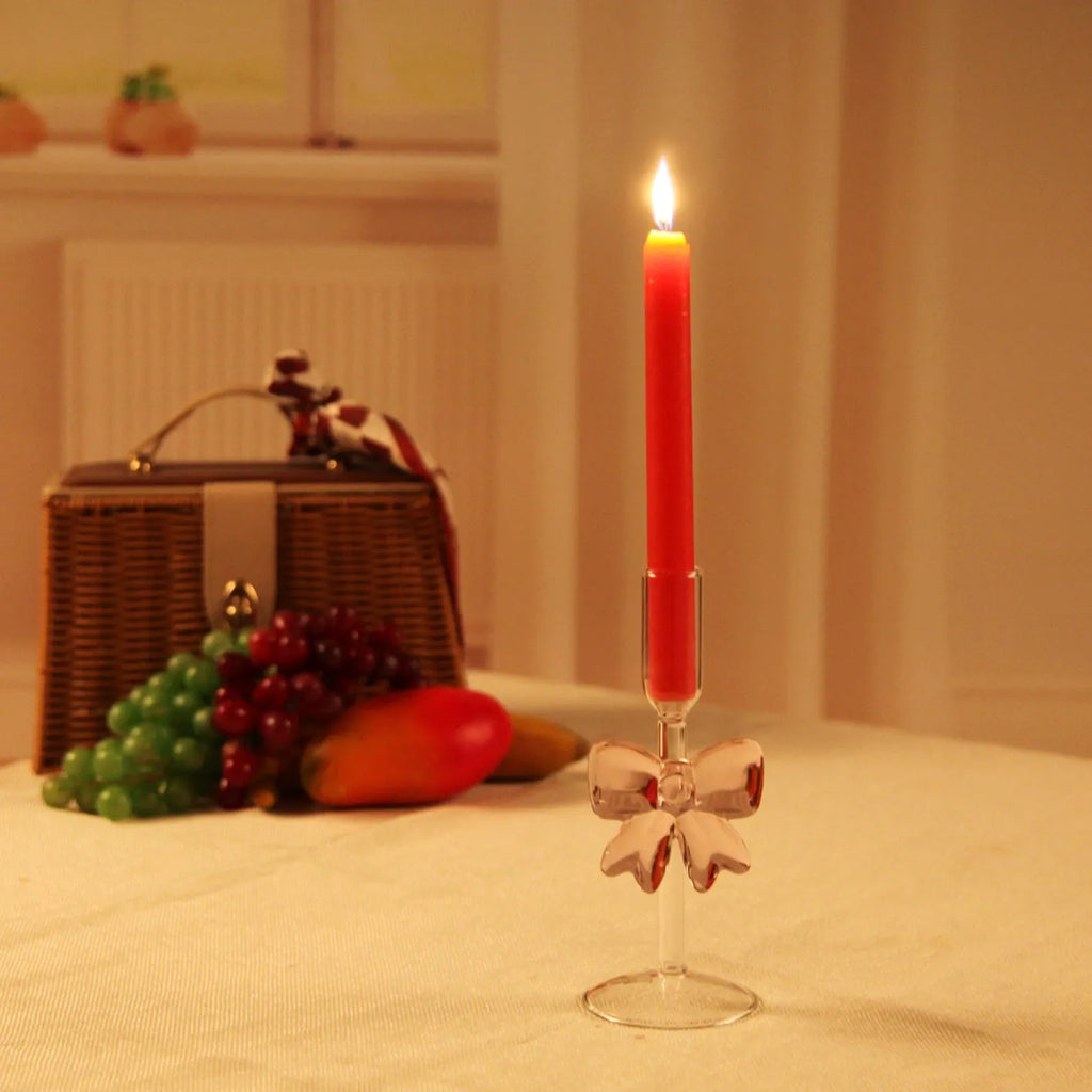 Set of three clear borosilicate glass candlesticks with large bow decorations on a table