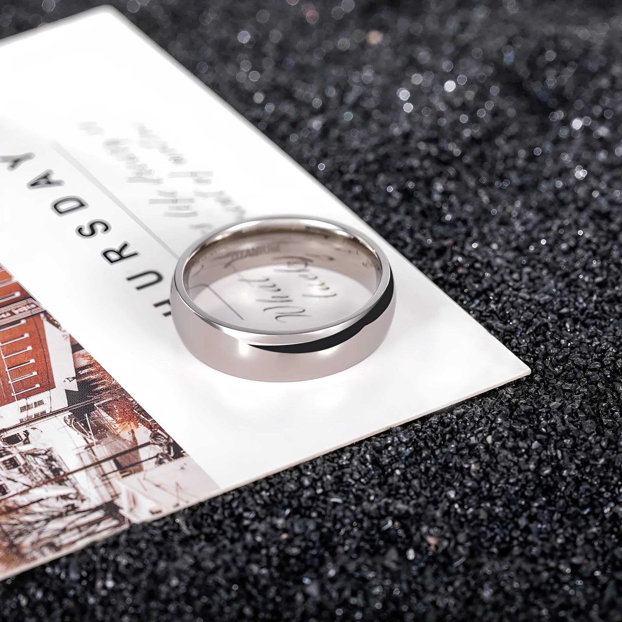 Silver titanium steel ring on a finger, showing a simple band design.