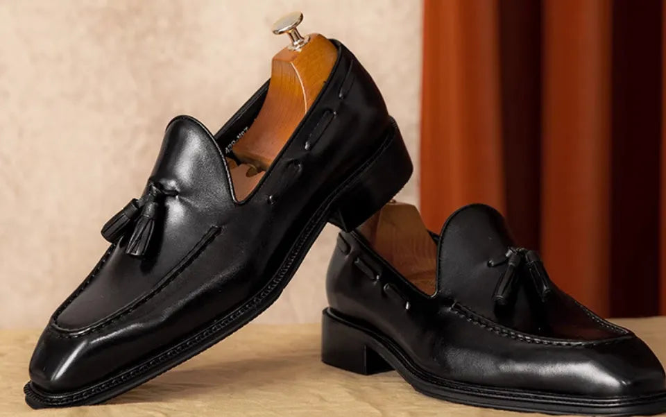 Men's black and brown genuine leather slip-on loafers with a polished finish and rubber sole.