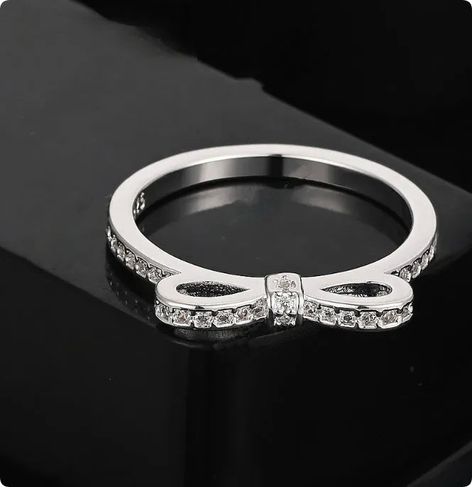 Silver bow-shaped ring with crystal rhinestones on finger