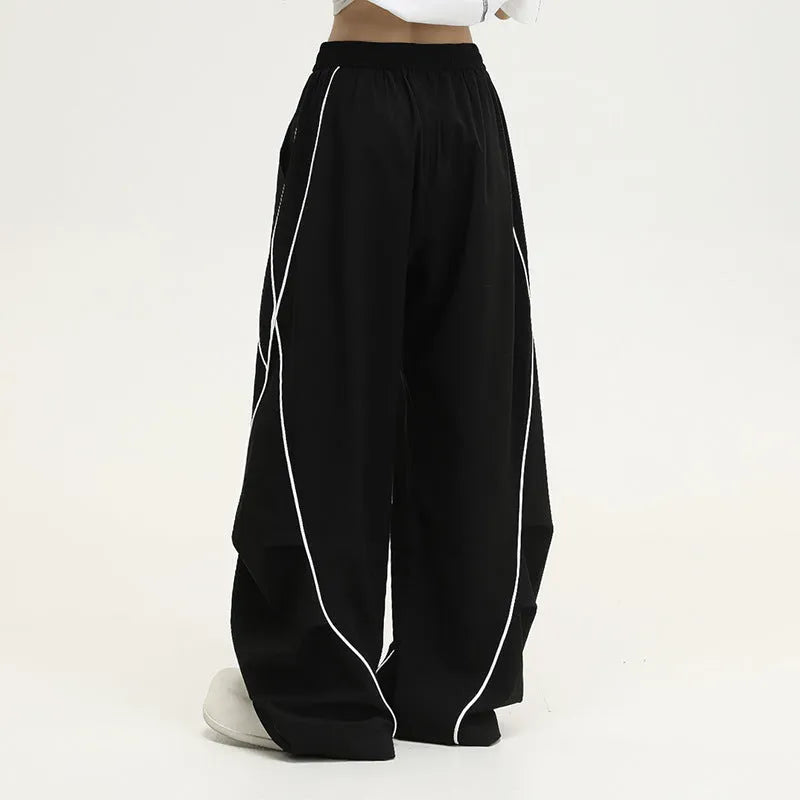 Black pleated wide-leg hip hop sports trousers on a hanger, showing loose fit and striped pattern.