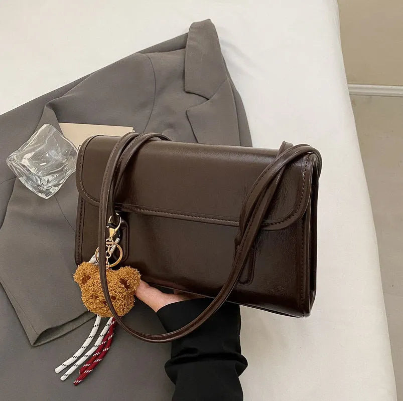 Brown women's Maillard-style PU leather shoulder bag with a double strap and a removable pendant accessory.