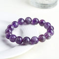 Natural Feather Amethyst crystal bracelet with Ruyi charm beads on a wrist.