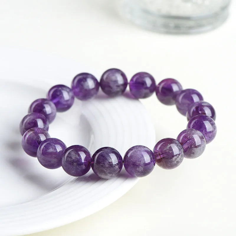 Natural Feather Amethyst crystal bracelet with Ruyi charm beads on a wrist.