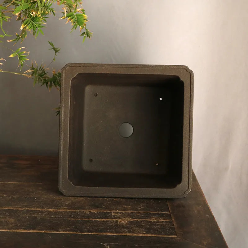 Purple sand square high basin flower pot with black ancient copper clay finish on a wooden table