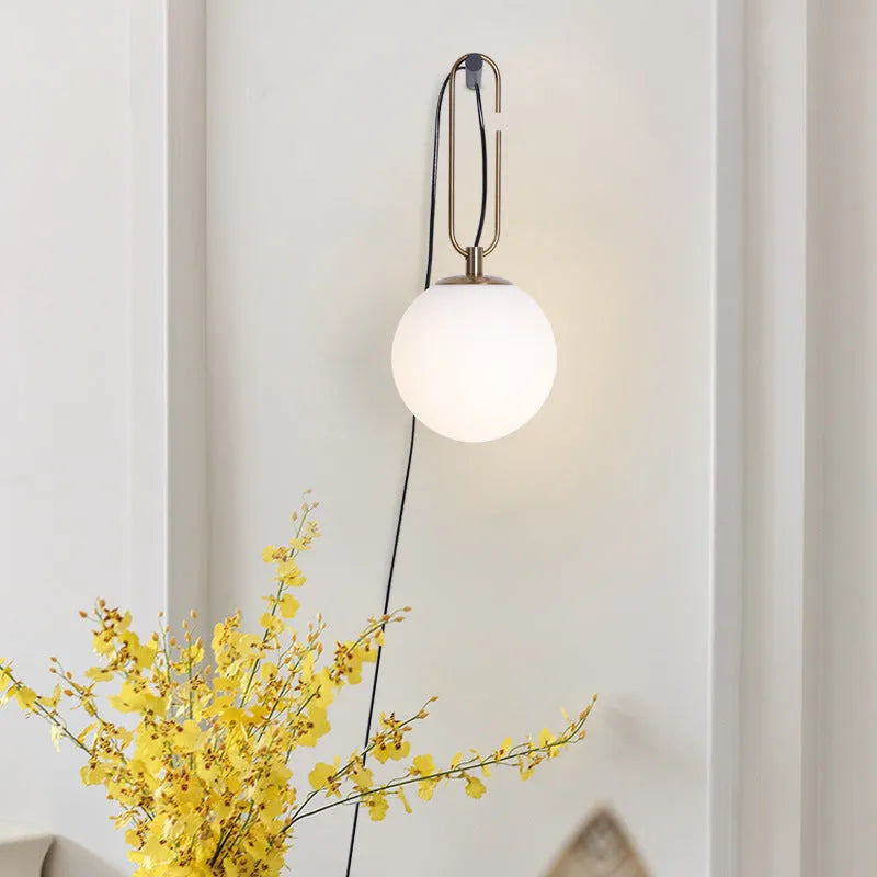 Contemporary clear glass wall light fixture with modern design on a white wall.