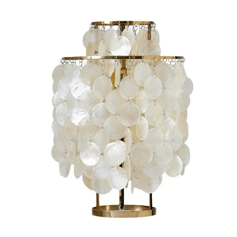 Creative modern shell-shaped table lamp in chrome or gold finish on a bedside table.