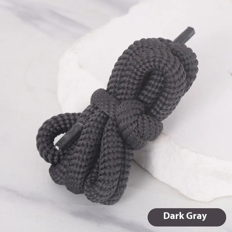 Oval cross-section shoelace adapter rope in various colours, shown next to a trainer and sweatshirt.