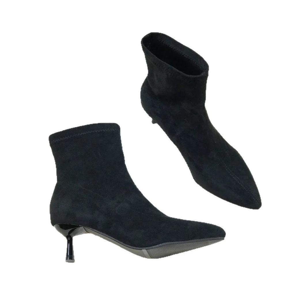 Black pointed toe women's ankle boots with stiletto heels on a neutral background.
