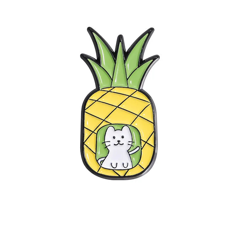 Colourful cartoon fruit and letter design metal brooch on a fabric background.