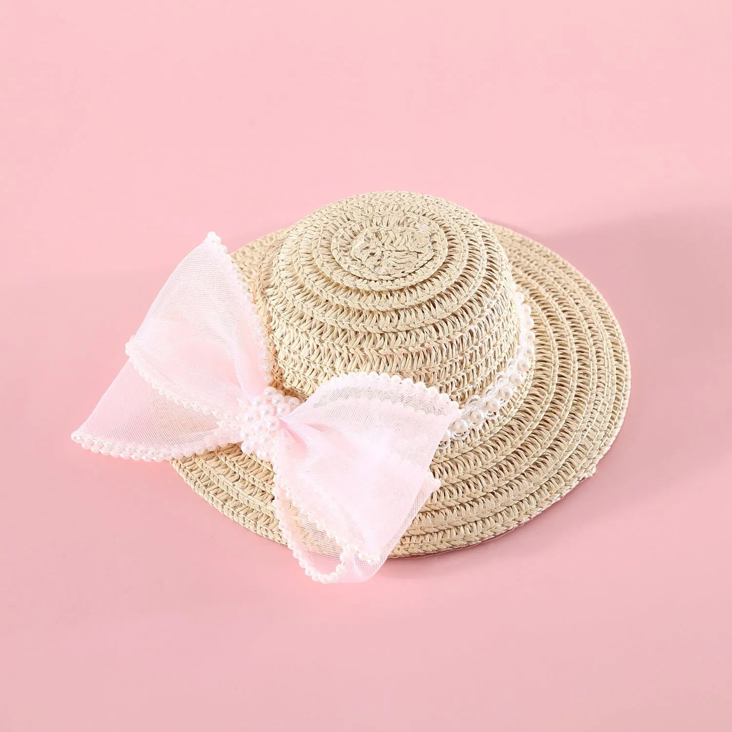 Cat wearing a woven straw hat with a pearl bow decoration in a princess style.