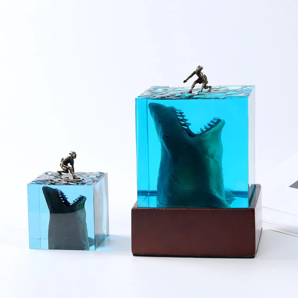 Close-up of a crystal resin shark surfer night light ornament on a dark surface.