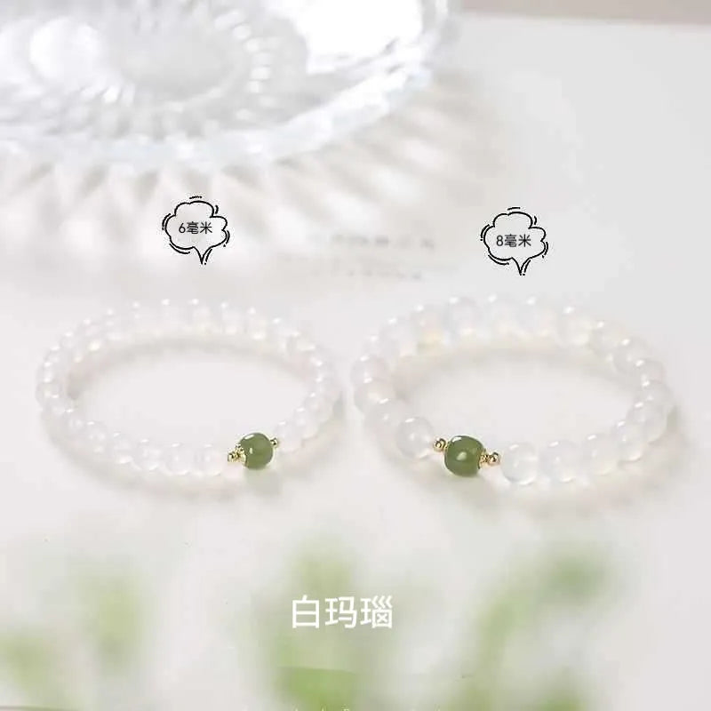Handmade white agate and cinnabar bracelet with text design on a wrist.
