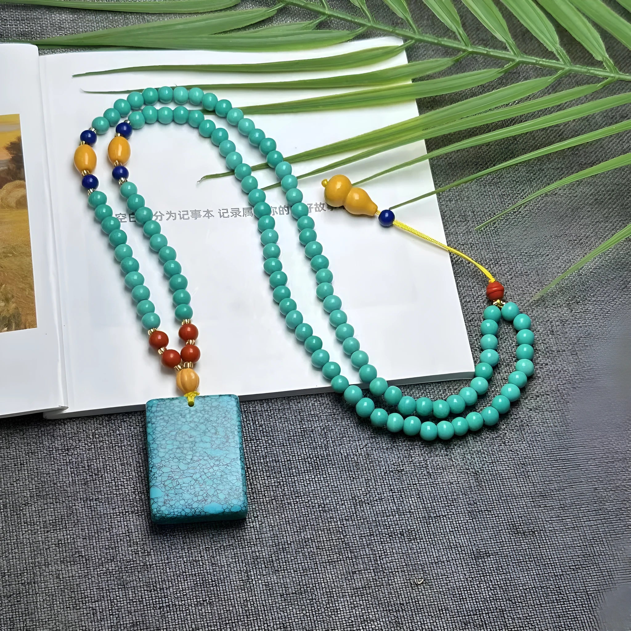 Turquoise lucky pendant necklace with hand-woven mesh flower design on a ball bead chain.