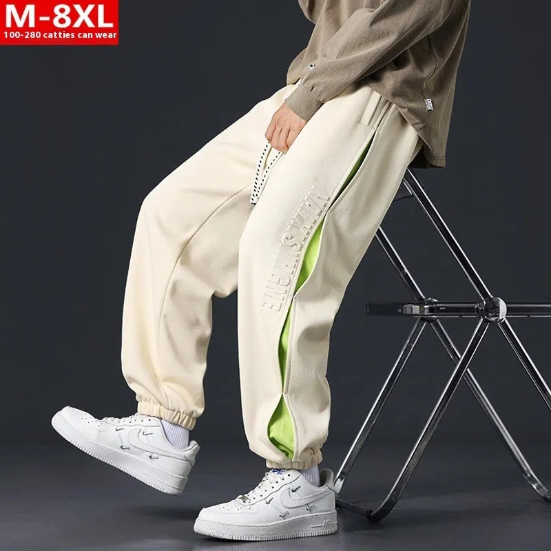 Men's loose black cotton trousers with white collage stitching print and banded ankle cuffs laid flat.