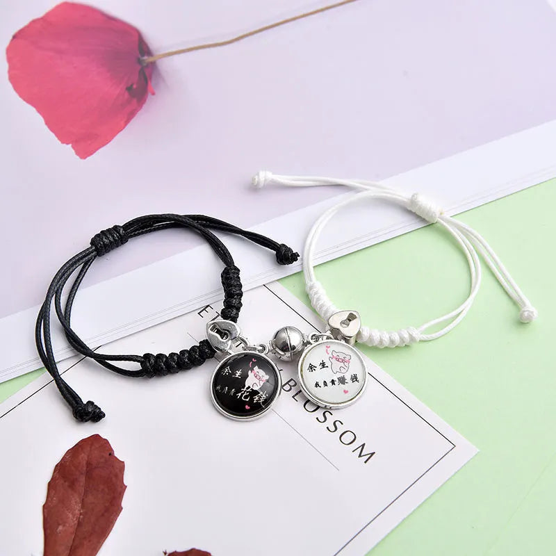 Pair of magnetic suction bracelets with alloy charms in various love and friendship themed designs on a wrist.