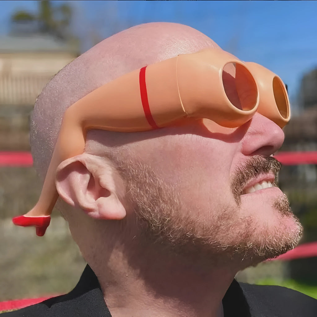 Orange plastic novelty sunglasses with a distinctive leg hip design on the frame.