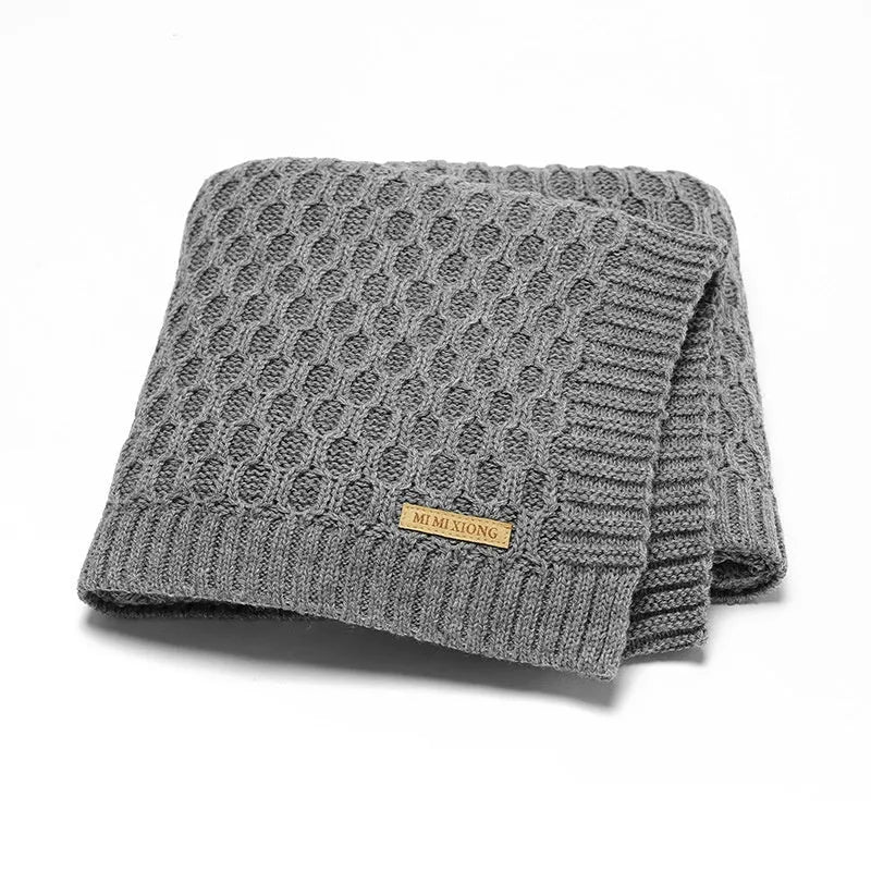 Solid colour infant blanket with textured lines, shown in a choice of colours including pink and beige.