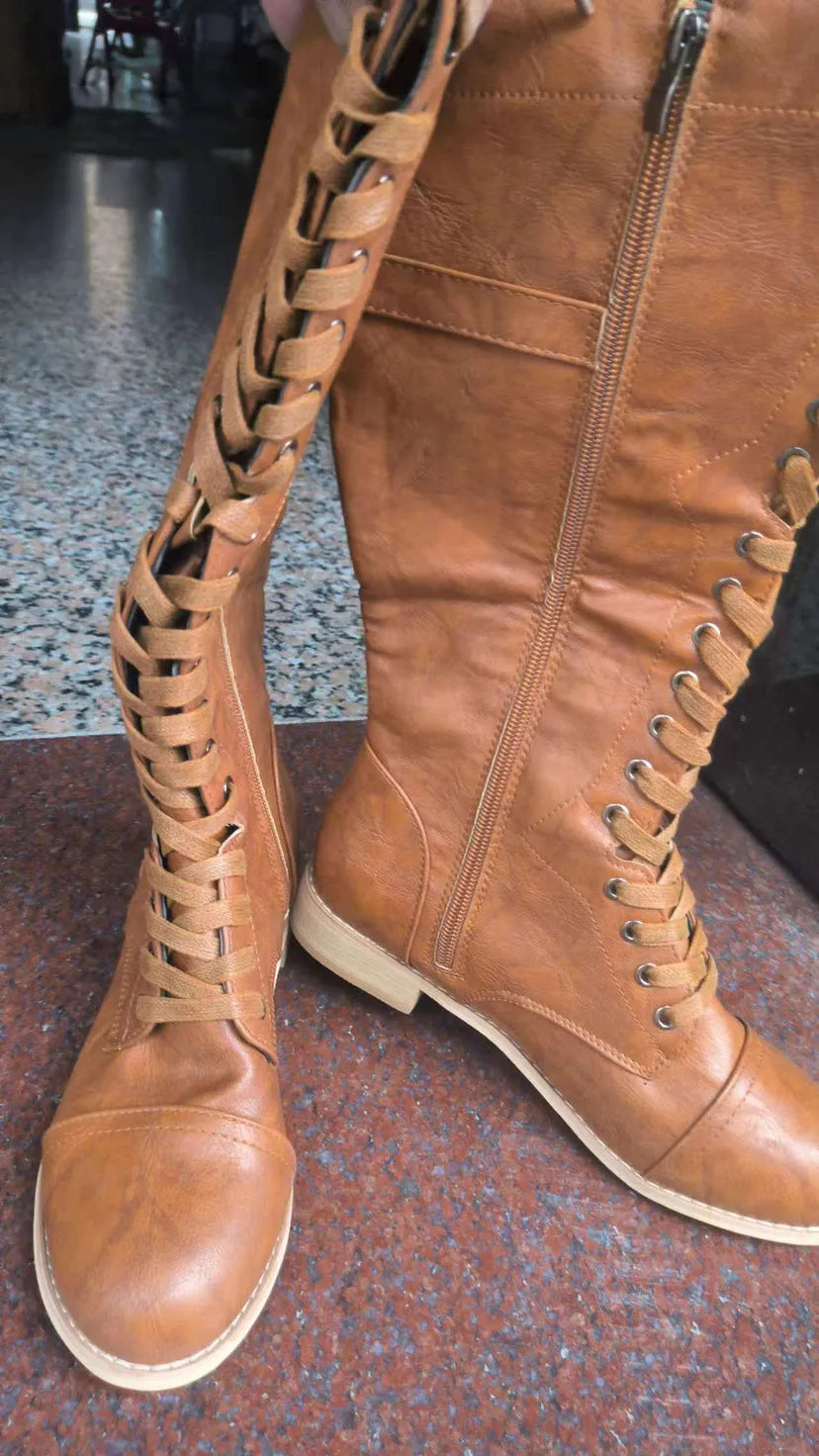 Women's black PU leather knee-high boots with a cross strap detail across the ankle.