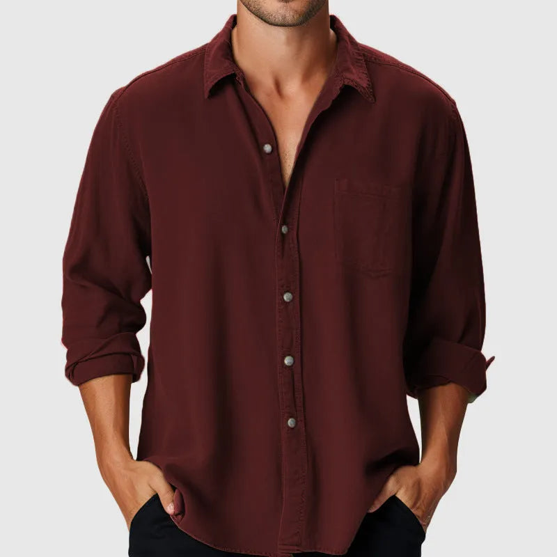 Man wearing a loose fit long sleeve beach shirt with a stand collar in a solid colour.