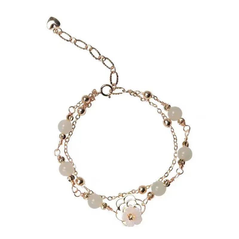 Yellow gold electroplated copper bracelet with a bells of Ireland butterfly, shell flowers, and Hetian jade accents.