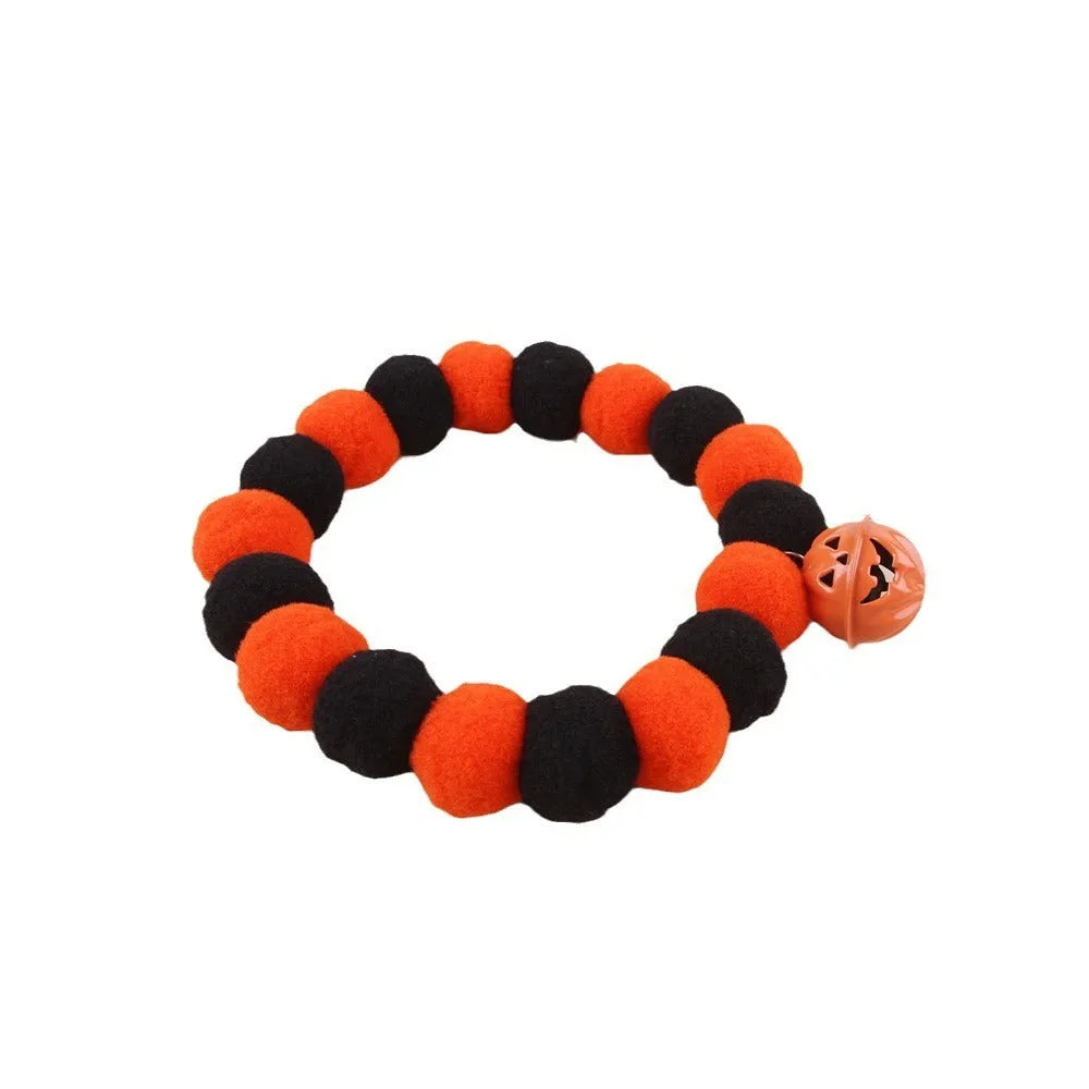 Orange Halloween cat collar with 'Naughty Cat' text and a detachable plastic pumpkin charm on a table.