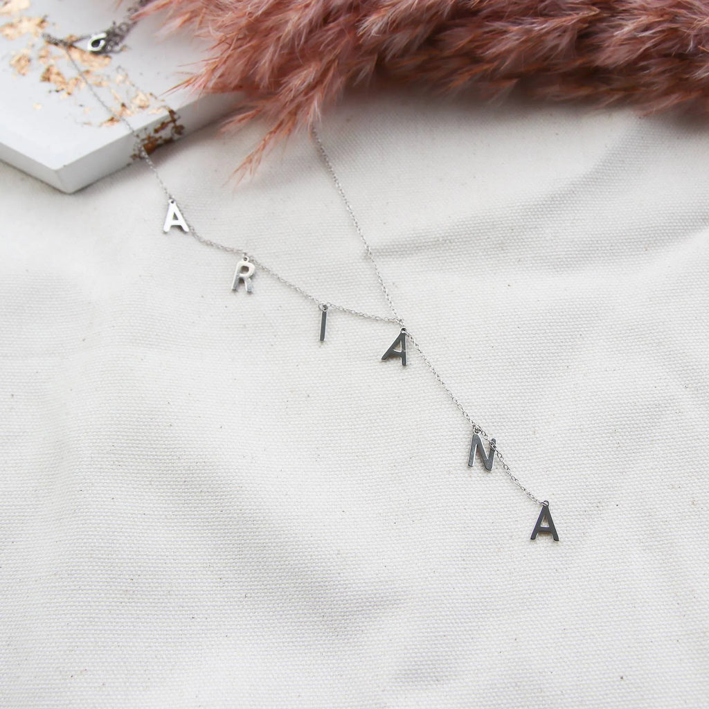 Gold lariat name necklace with bubble letters on adjustable chain, isolated on white background