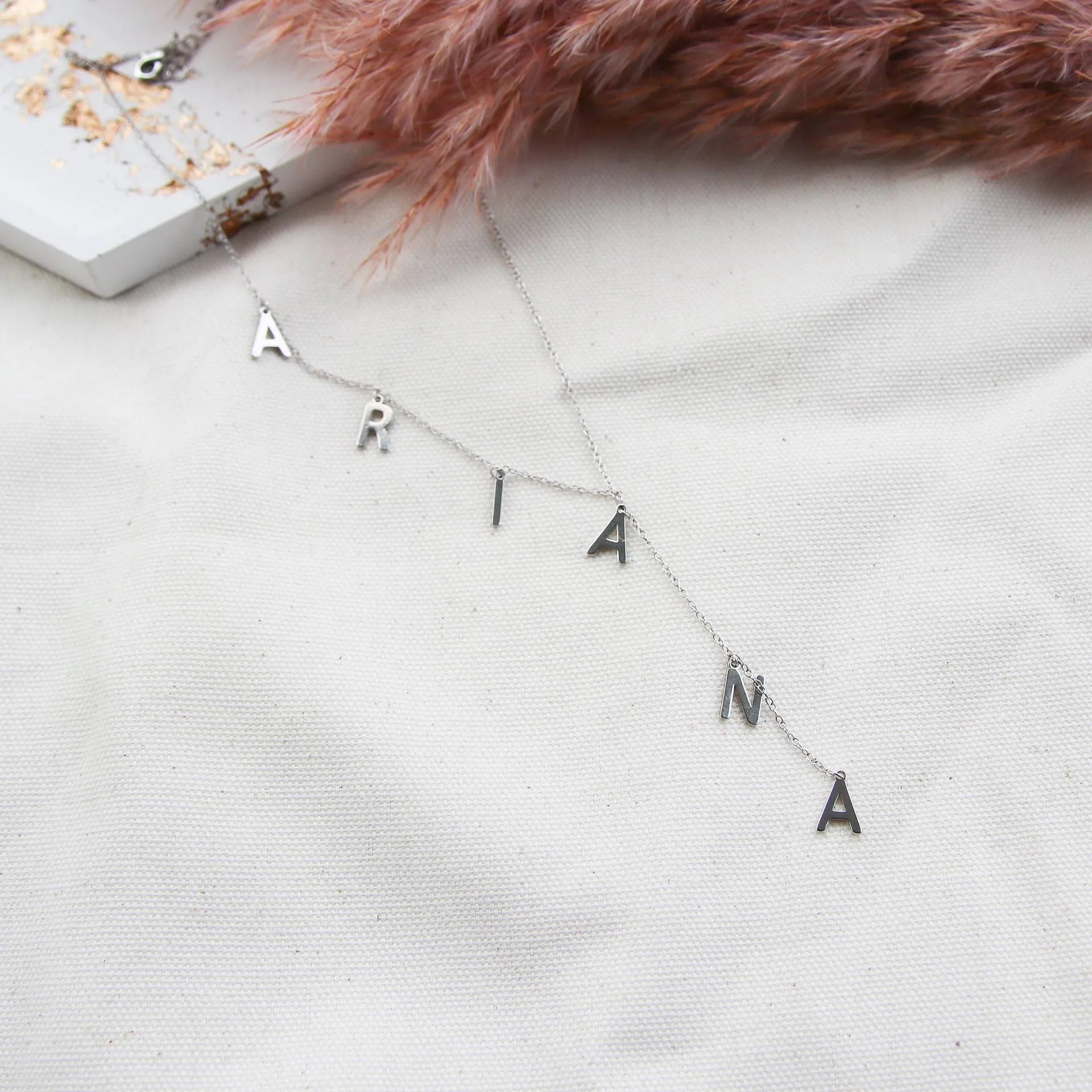 Gold lariat name necklace with bubble letters on adjustable chain, isolated on white background