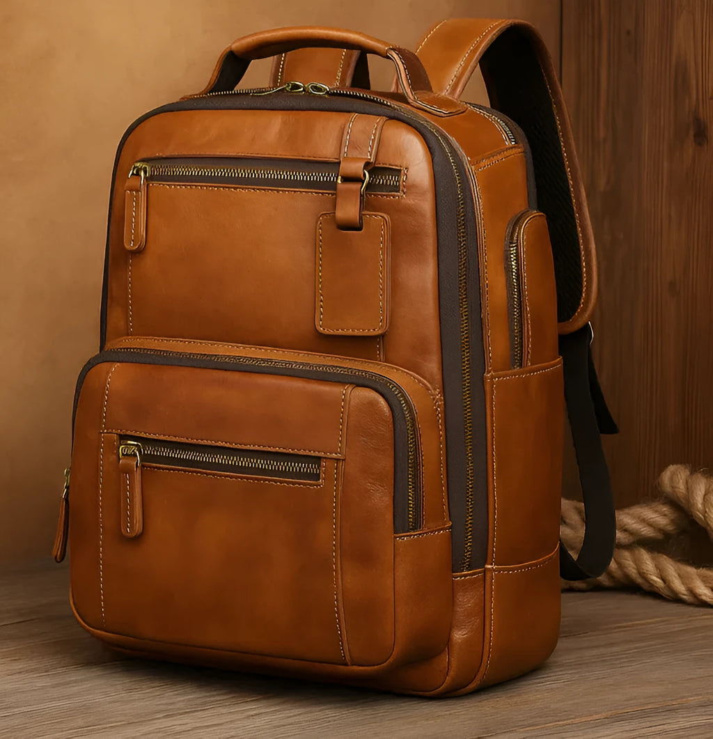 Bronze real leather backpack with structured form, zipper closure, top handle, and adjustable shoulder straps.