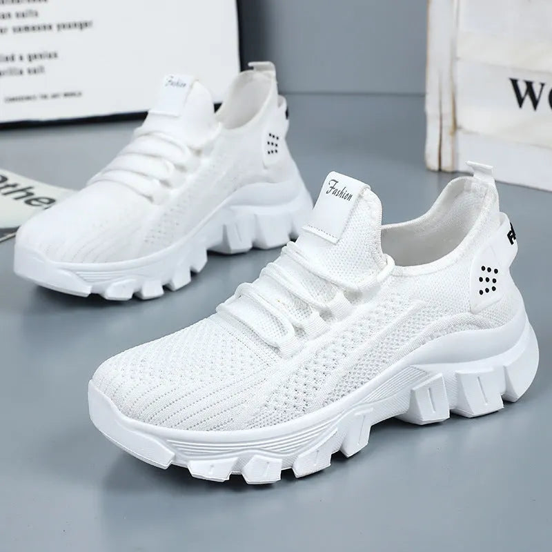 Women's white Flyknit running sneakers with round toe, flat heel, and thick PVC sole on a light background.