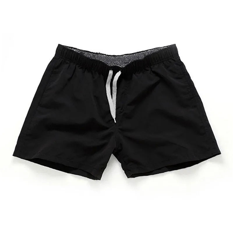 Men's black surf shorts made from polyester fabric with a straight leg opening, shown on a size chart.