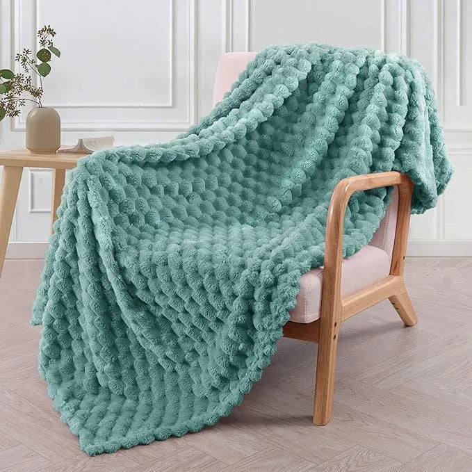 Soft camel-coloured plaid fleece blanket for children folded on a bed.