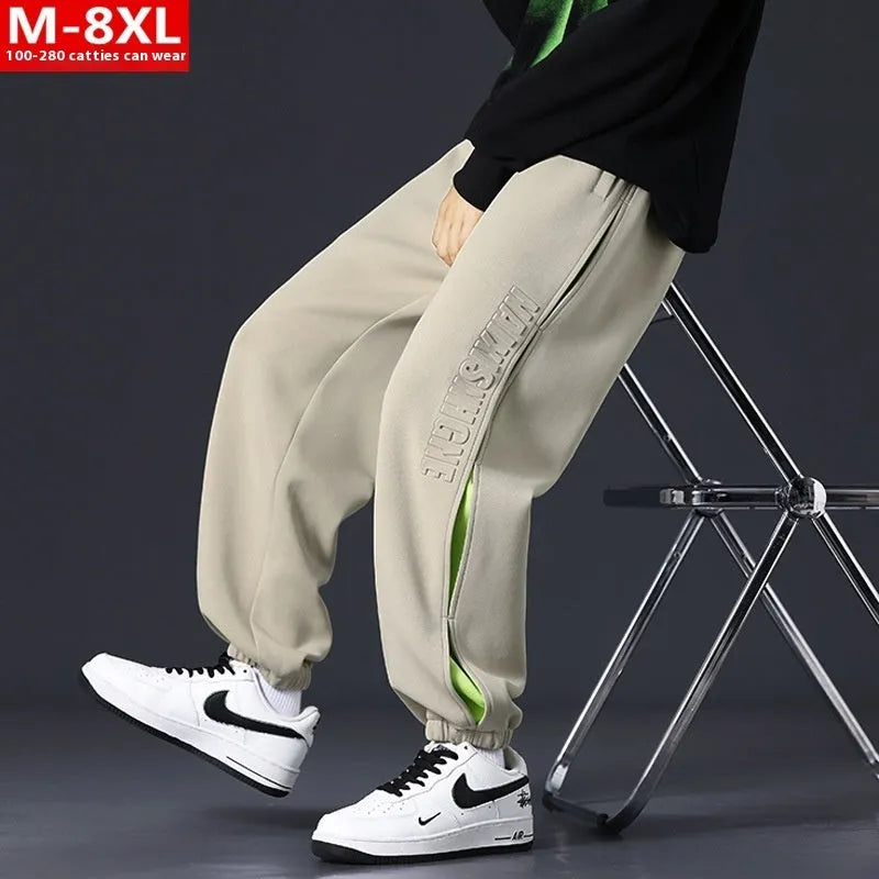 Men's loose black cotton trousers with white collage stitching print and banded ankle cuffs laid flat.