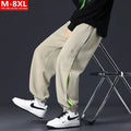 Men's loose black cotton trousers with white collage stitching print and banded ankle cuffs laid flat.