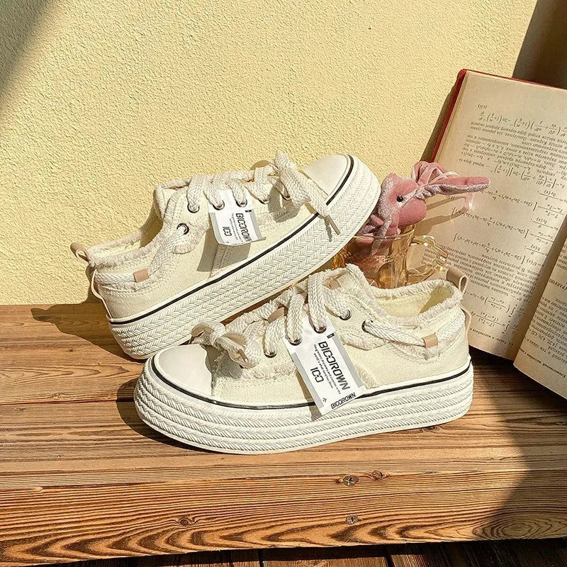 Women's low-top canvas shoes in solid colour with vulcanised rubber sole, available in beige, black, and pink.