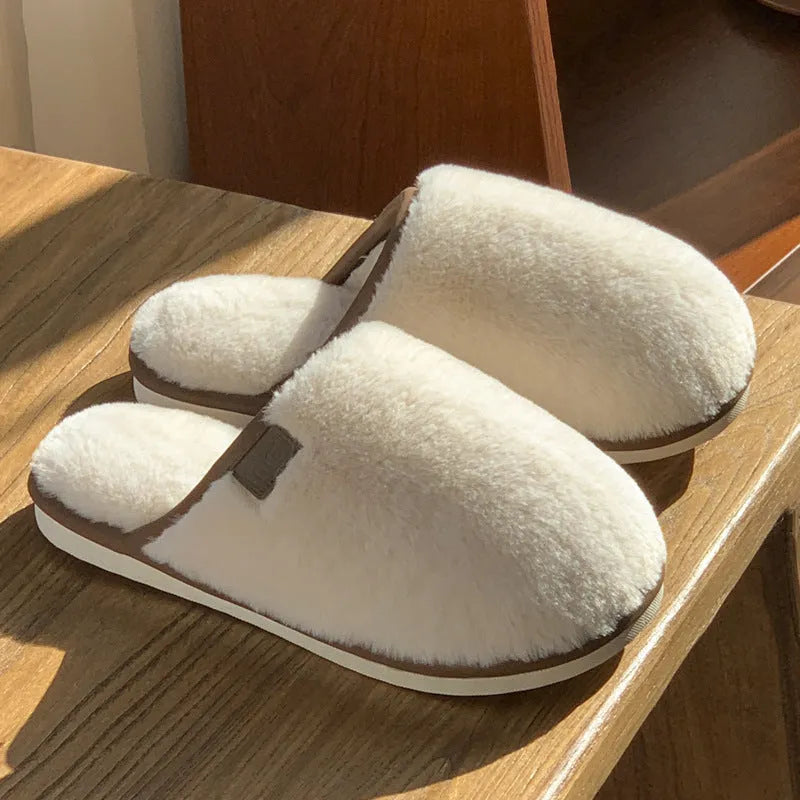 Solid colour PVC plush winter house slippers on a wooden floor.