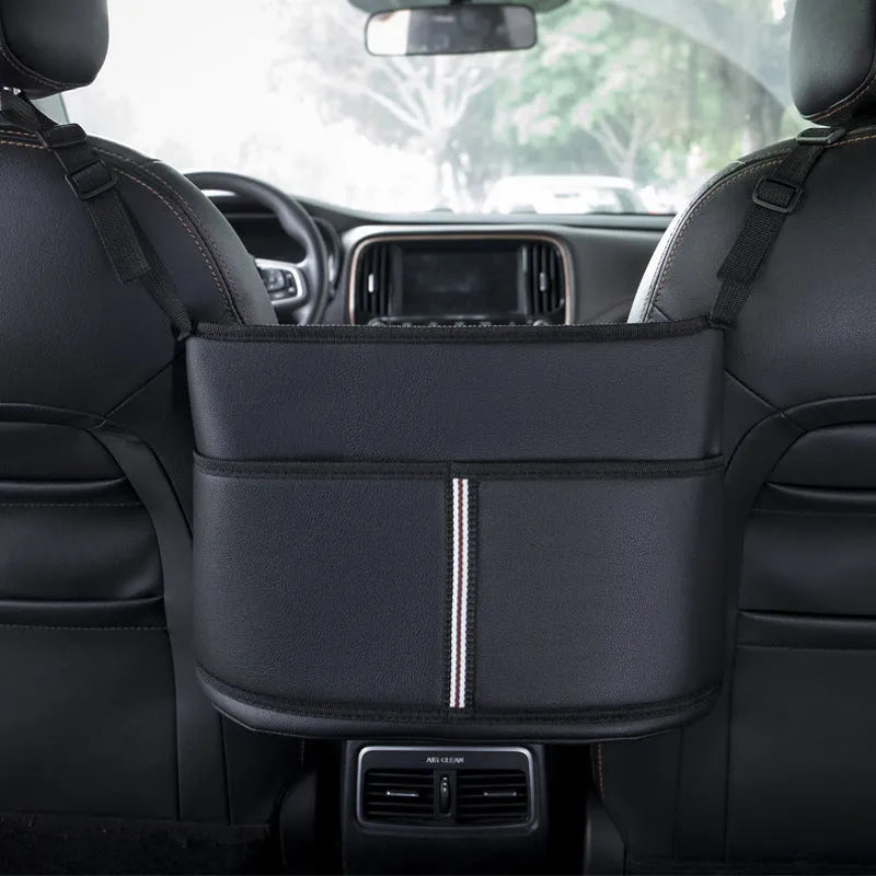 Black leather car interseat storage bag holding a tissue box, hanging between vehicle front seats.