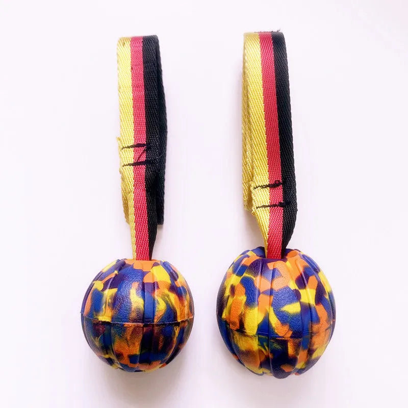 Yellow and camouflage coloured EVA foam floating dog ball with string attached for fetch and water training.