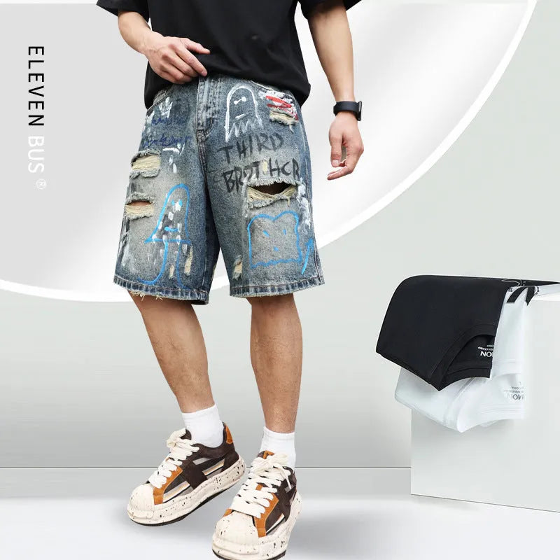 Blue men's denim shorts with ripped knees and graffiti detailing, showing straight leg cut and zipper fly.