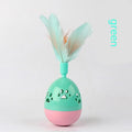 Green cat tumbler bell interactive toy with hollow footprints and feathers on a light floor