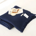 Cotton four-layer gauze blanket with tassel trim in various colours draped over a sofa.