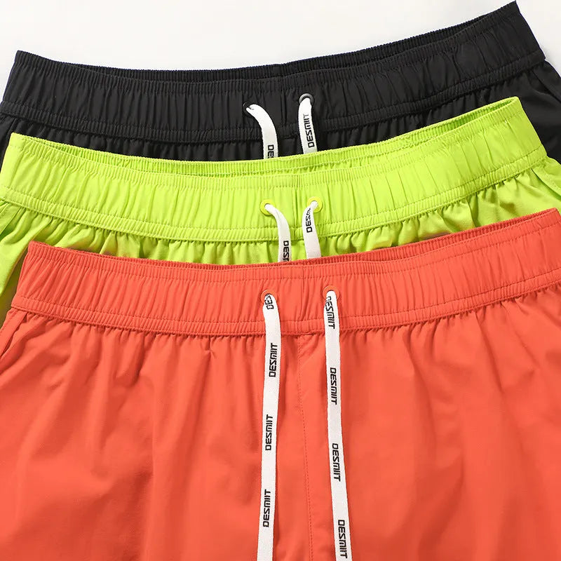 Men's loose fit beach shorts in fluorescent green, orange red, and black colours with micro-elastic polyester fabric