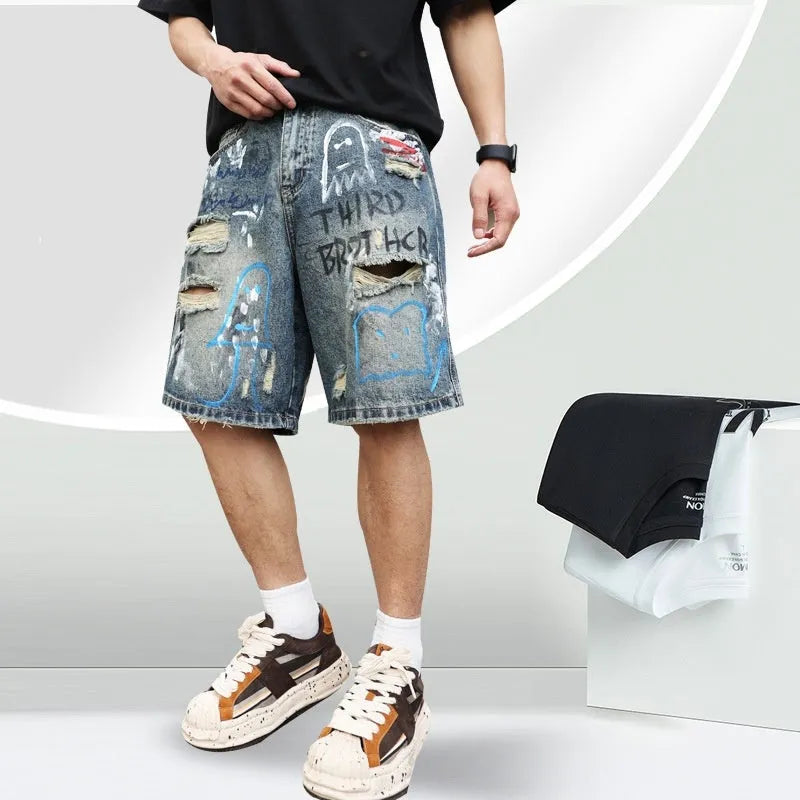 Blue men's denim shorts with ripped knees and graffiti detailing, showing straight leg cut and zipper fly.