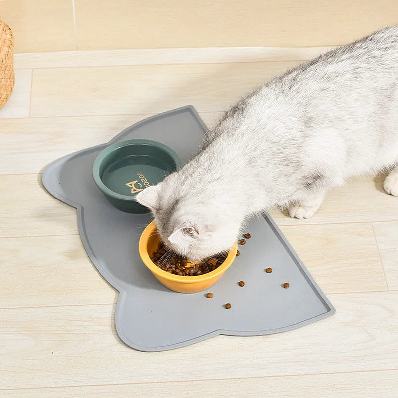 Blue silicone cat head-shaped pet feeding mat on a wooden floor.
