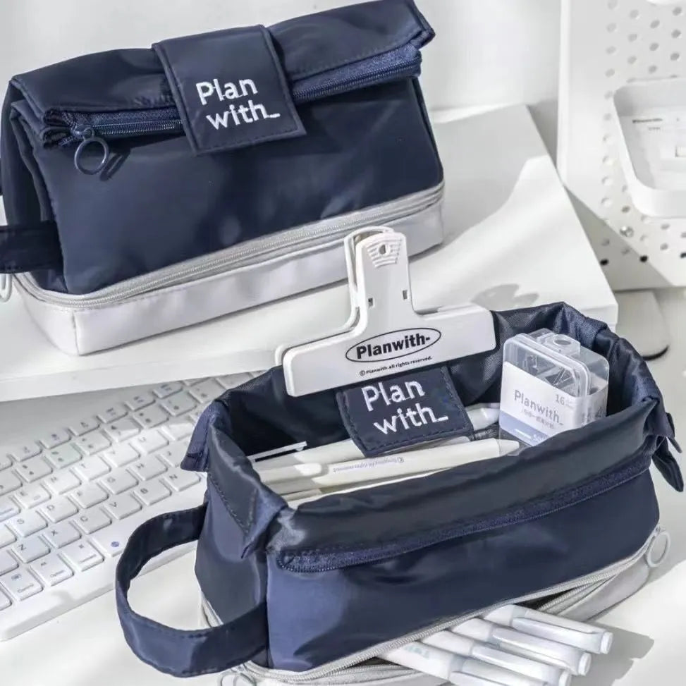 A dark blue folding double-layer pencil case made from polyester fabric, shown open to reveal internal dividers.