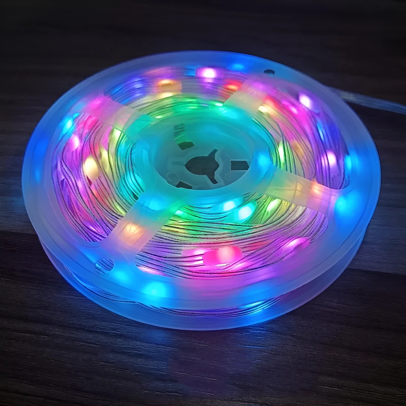 10 metre long multicolour LED party light string with 100 lights coiled on a table next to its control switch.