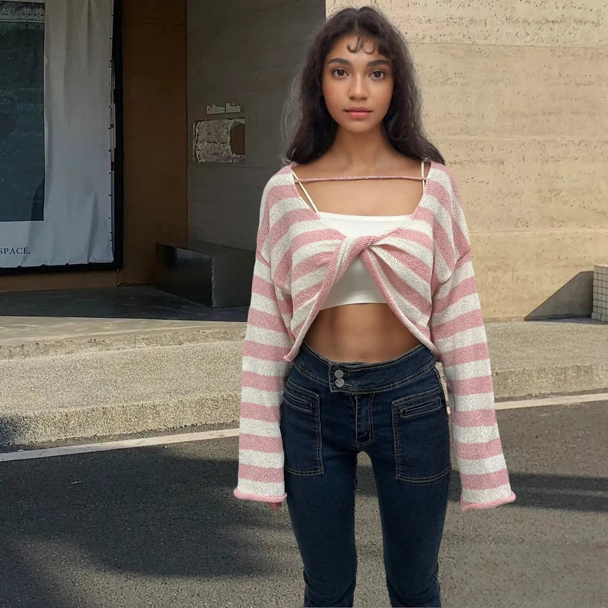 Woman wearing a striped long-sleeved cropped sweater in mercerised cotton, showcasing front and back wearable design.