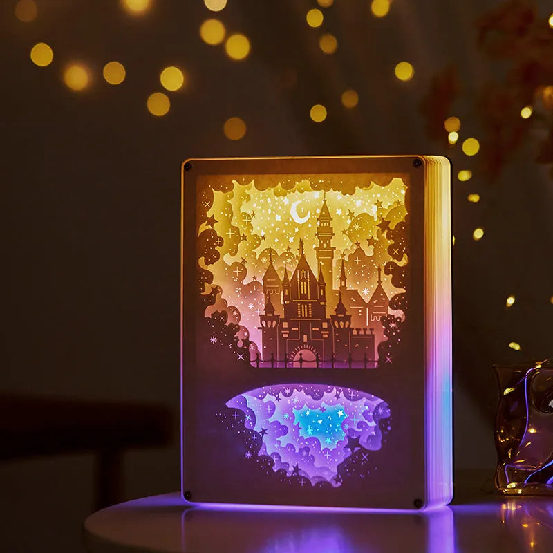 Modern romantic night light with three-dimensional paper carving design and remote control on a bedside table.